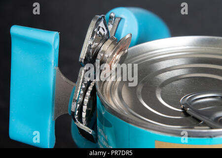 Close view of a can opener opening a tin can Stock Photo