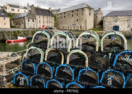 Lobster traps on stone dock of Old Harbourside Portsoy with stone Portsoy Marble warehouse Aberdeenshire Scotland UK Stock Photo