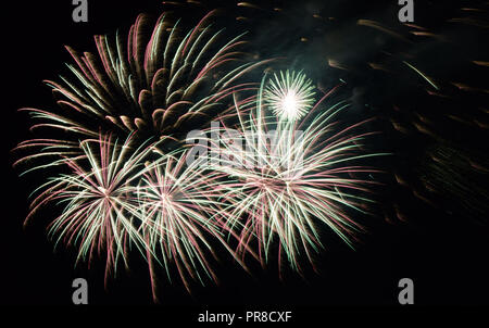 green and silver colored fireworks, multicolour festive fireworks in night sky Stock Photo