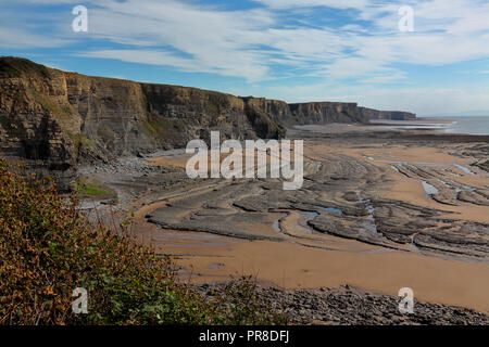 View south along the cliffs towards Monk nash point with the tide fully out exposing the eroded roack layers amid the sands on this "Heritage" coast. Stock Photo
