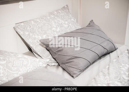 Gray pillows setting on grey and white color scheme bedding Stock Photo