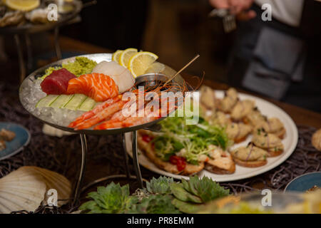 Mixed sliced fish sashimi and shrimps on ice in black bowl. Sashimi Salmon Tuna Hamachi Prawn and Surf Calm set, raw fish, japanese food in Asian rest Stock Photo