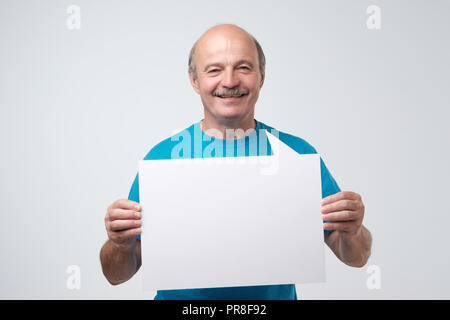 Senior hispanic man with mustache holds the white sign in a studio white background Stock Photo