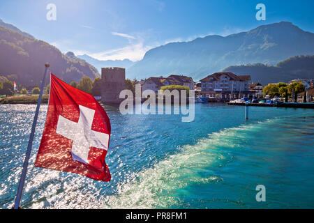 Lake Luzern boat flowing from Stansstad village with Swiss flag, fabulous landscape of Switzerland Stock Photo