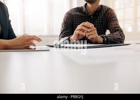 Close up shot focusing on hand gestures of business colleagues during a meeting. Two business people sitting at the table discussing work. Stock Photo