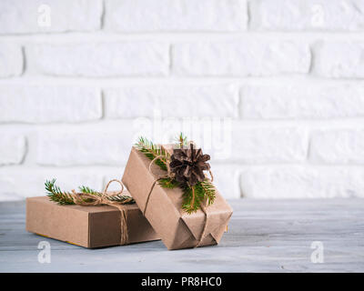 Rustic gift boxes on gray table and white brick wall. Christmas and winter holiday gifts with copy space Stock Photo