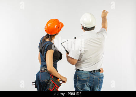 contractors people discussing the plan of building over white background. Foreman with builder woman wearing helmets. Stock Photo