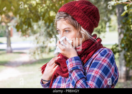 Woman portrait outdoor sneezing because cold and flu