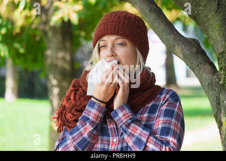 Woman portrait outdoor sneezing because cold and flu