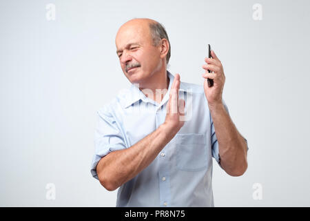 Mature handsome man refusing to speak on the phone over isolated background turning his face from it Stock Photo
