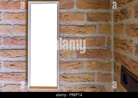 empty small long rectangular picture frame hanging on a brick wall close to a corner Stock Photo