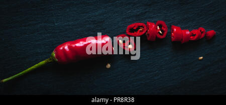 Chopped red chili pepper on dark background, top view Stock Photo