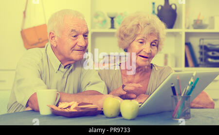 Portrait of cheerful mature spouses using laptop at home Stock Photo