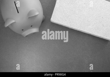 terracotta piggy bank and wall insulation panel on a stone background - top view Stock Photo