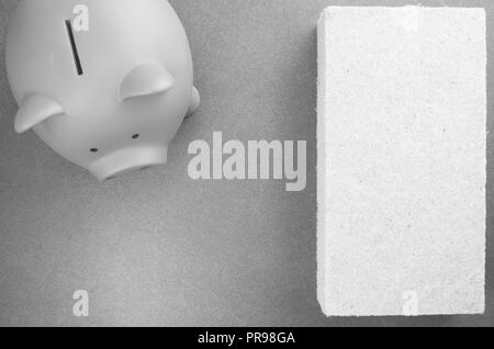 terracotta piggy bank and wall insulation panel on a stone background - top view Stock Photo