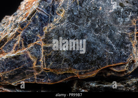 Biotite (black mica) mineral on black background. Stock Photo