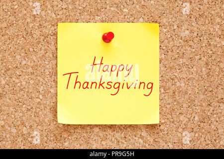 Happy Thanksgiving handwritten on yellow sticky note pinned on cork bulletin board. Stock Photo