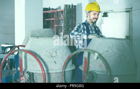 Smiling male worker using concrete mixer for construction work at workplace Stock Photo