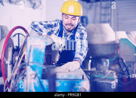 Adult guy is using disk saw to cut tile at workshop. Stock Photo
