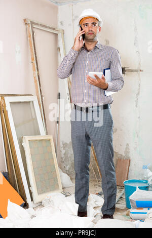 Positive man engineer talking on the mobile phone with tablet in the hand Stock Photo
