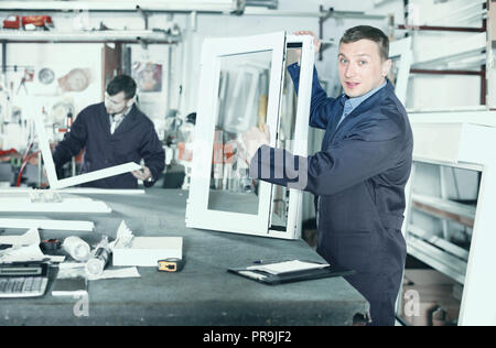 Two smiling cheerful positive careful workmen inspecting PVC manufacturing output in workshop Stock Photo