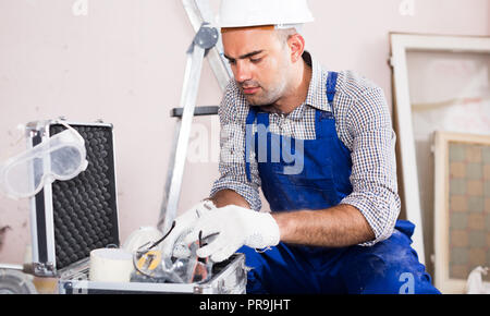 Portrait of worker builder searching tools for repair in toolbox Stock Photo