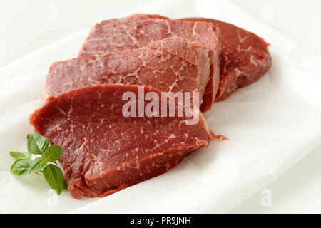 Raw marbled beef  and basil leaf on a cutting board Stock Photo