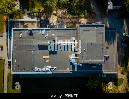 Aerial view of building roof being reconstructed. Sunny autumn evening. Stock Photo