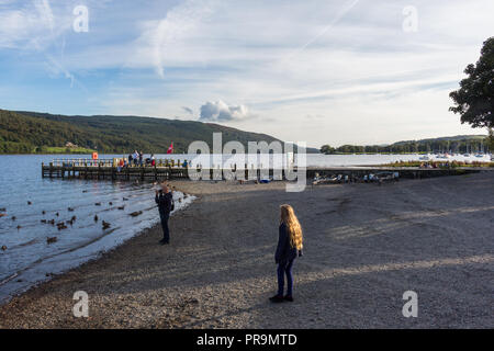 People relaxing in the evening on shores of Coniston Water, Coniston, Lake District, Cumbria, England. Stock Photo