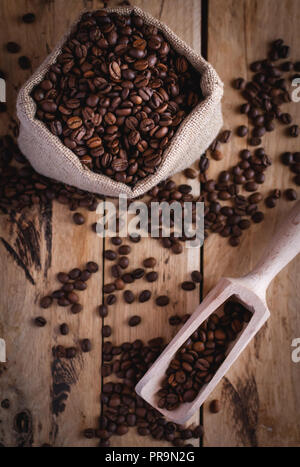 Coffee beans in jute sack and scoop on wooden background, top view Stock Photo
