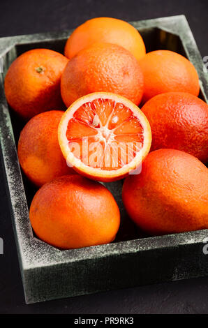 Blood oranges in wooden tray on dark background Stock Photo