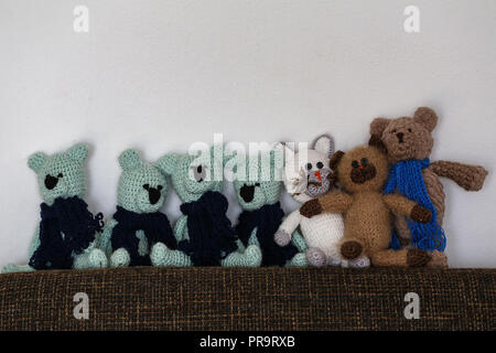 Homemade knitted toys stand against the wall Stock Photo