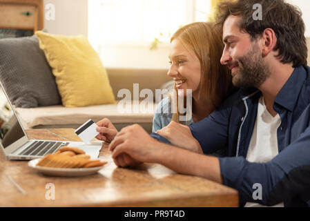 Young couple doing shopping online in internet and using a credit card Stock Photo