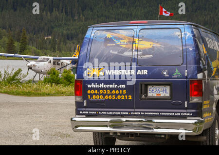 WHISTLER, BC, CANADA - JUNE 2018: Courtesy shuttle bus parked near the seaplane terminal in Whistler. A plane is in the background. Stock Photo