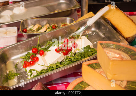 Salzburg, Austria - June 1, 2017: White cheese with cherry tomatoes and rucola surrounded by other various kinds of cheese for sale on farmers market. Stock Photo