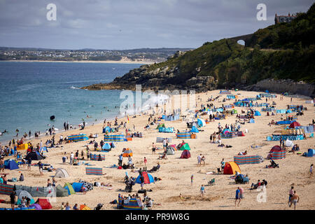 Busy tourist attraction St Ives beach front town in Cornwall, England, holiday makers on deackchais on the sand beach Stock Photo