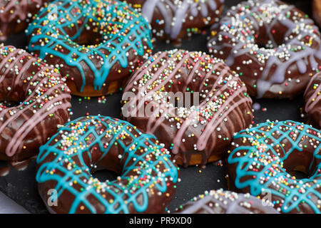 Chocolate covered donuts with holes and sprinkles in pink and blue Stock Photo