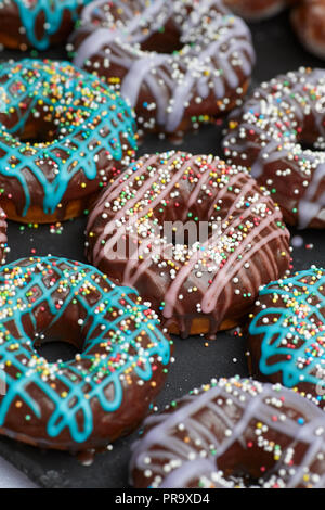 Chocolate covered donuts with holes and sprinkles in pink and blue Stock Photo