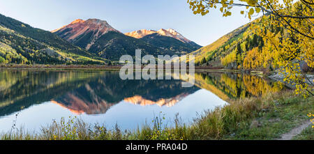 The Red Mountains and golden aspens on Hayden Mountain reflected in Crystal Lake in the Uncompahgre National Forest south of Ouray, Colorado.  (panora Stock Photo