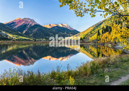 The Red Mountains and golden aspens on Hayden Mountain reflected in Crystal Lake in the Uncompahgre National Forest south of Ouray, Colorado. Stock Photo