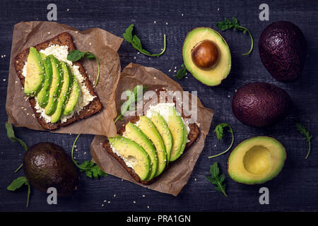 Sandwiches with rye bread, fresh sliced avocado and arugula Stock Photo