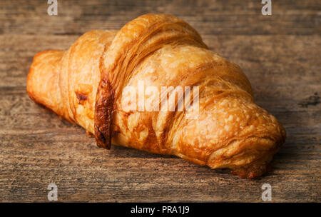 single fresh croissant on wooden background Stock Photo