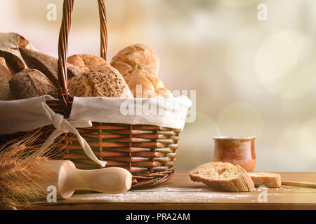 Assortment of breads over a wicker basket  on a table in a rustic kitchen. Horizontal composition. Front view Stock Photo