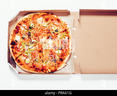Close-up round baked pizza in open cardboard box on white background, top view. Stock Photo