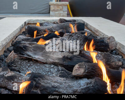 Close up of logs burning in a large, white, stone fire pit Stock Photo