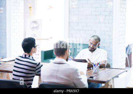 Mixed race manager analyzing statistics presented by staff Stock Photo