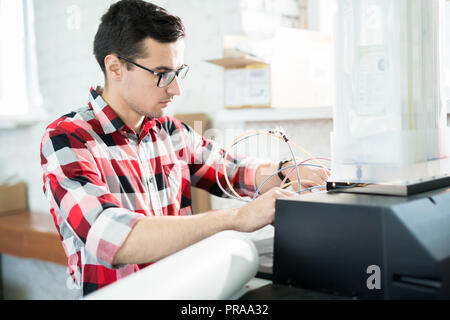 Busy engineer repairing printer in office of printing company Stock Photo