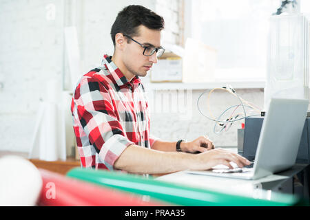 Serious technician testing printer on laptop Stock Photo