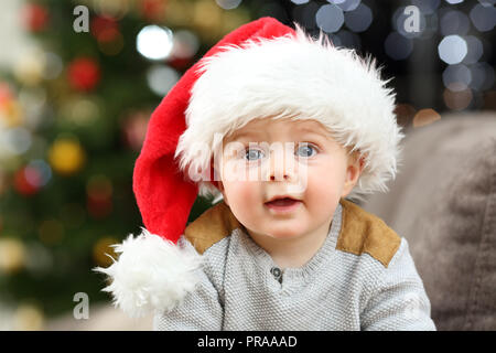 Portrait of a baby wearing santa hat in christmas on a couch in the living room at home Stock Photo