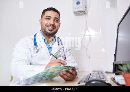 Middle-Eastern Doctor Posing at Desk Stock Photo